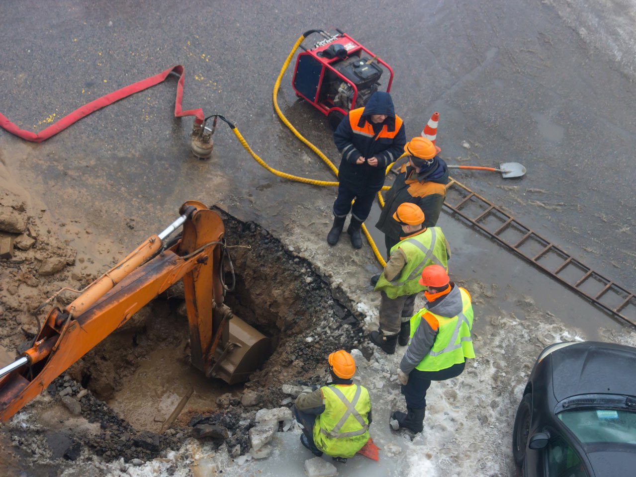 construction workers hovered around a hole at a roadside job site