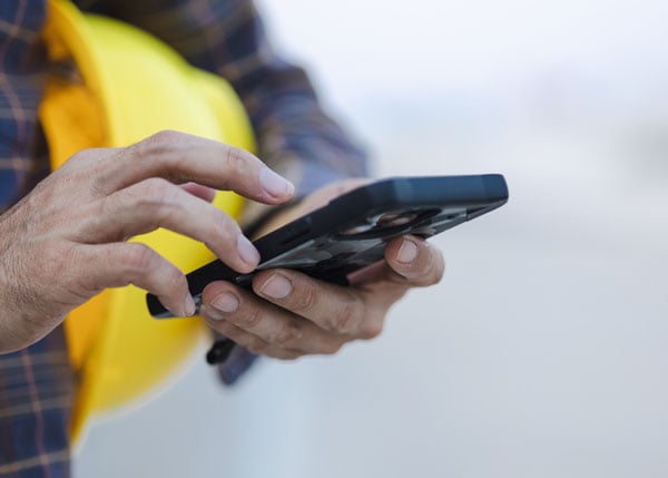 construction worker holding and tapping a mobile device