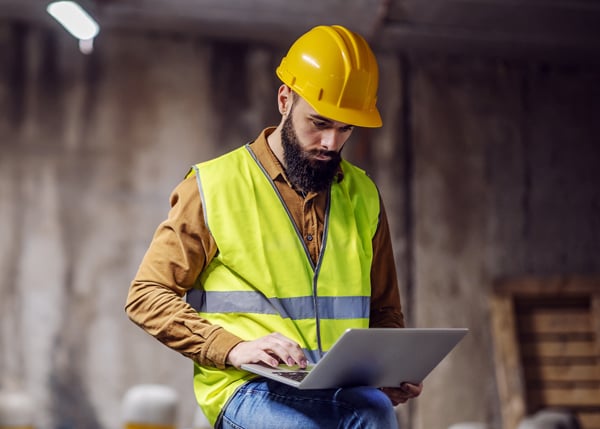 construction worker ooking at laptop device