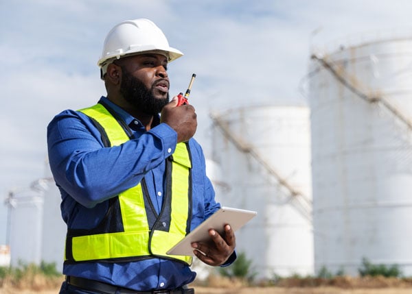 construction worker on walkie talkie while holding a tablet