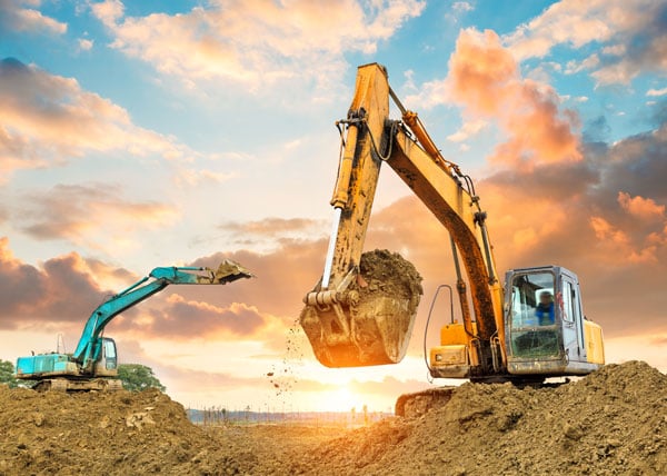 excavators on construction site on sunset backdrop