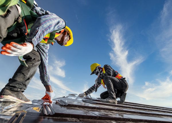 two construction workers working on roof
