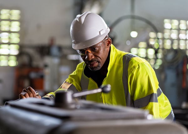 worker working with heavy machine with safety uniform goggles and helmet